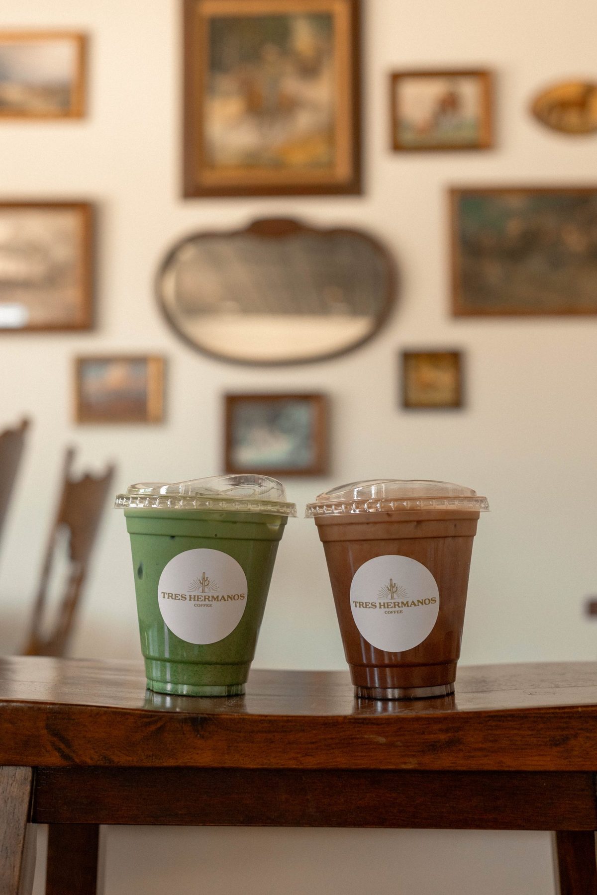 Iced matcha and mocha on a table below the gallery wall