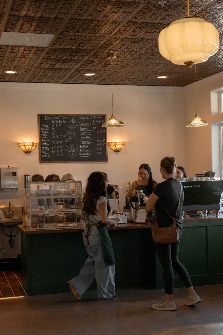 Baristas at the green counter under the chalkboard menu