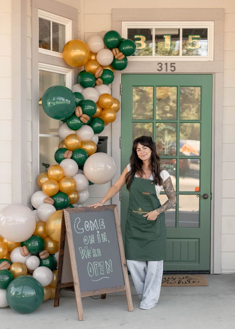 Owner beside the come-on-in chalkboard at the Templeton door